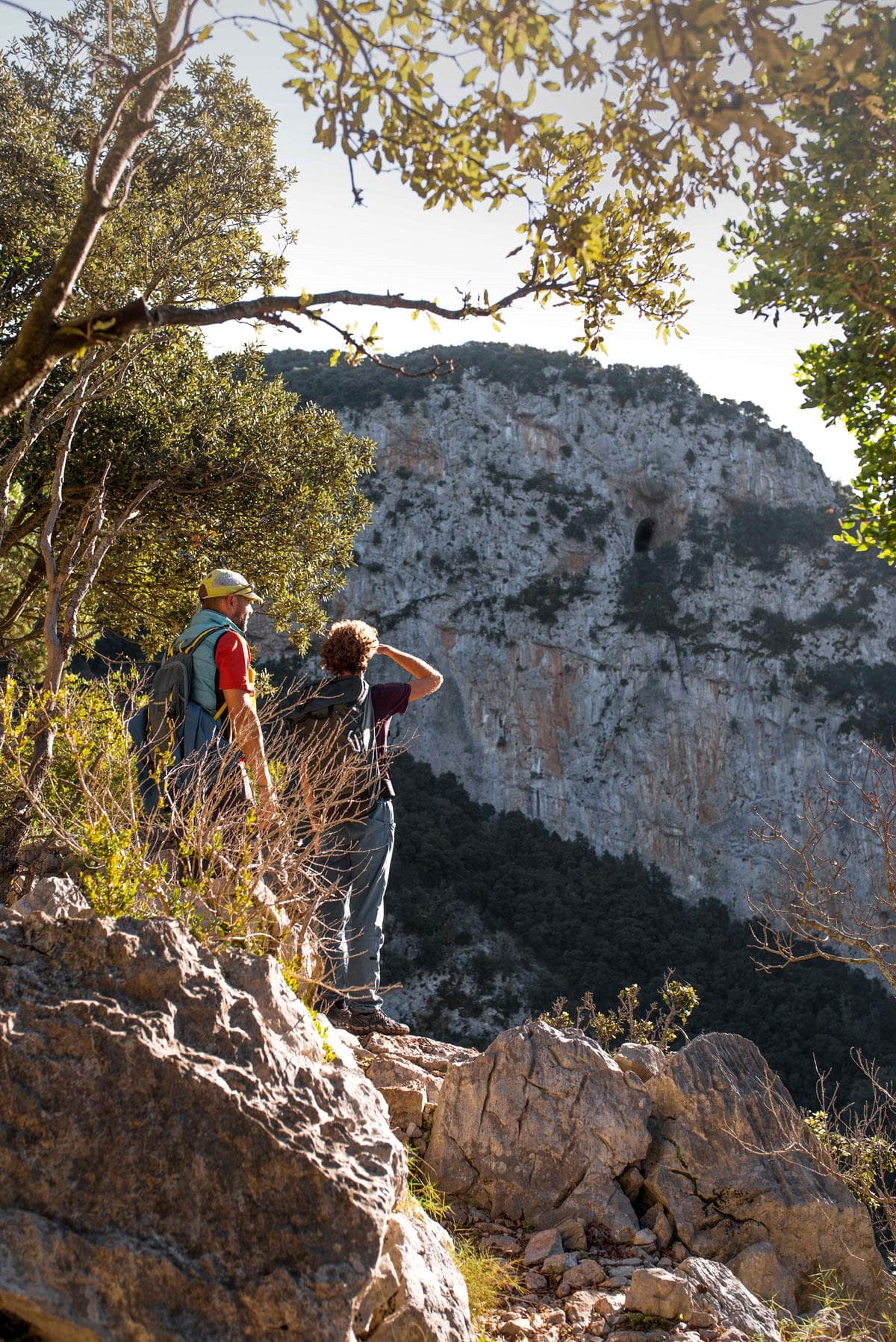 Dos excursionistes contemplen la paret de la Cova del Bisbe